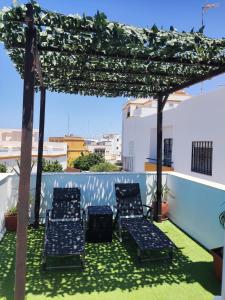 un groupe de chaises sous une pergola sur un toit dans l'établissement Alojamiento Los Corrales, à Chipiona