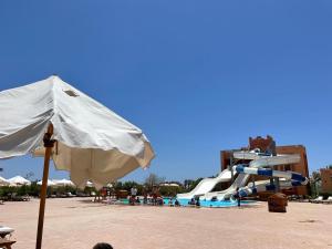 a pool with a slide and an umbrella and a water park at Dream Lagoon Resort & Aqua Park in Marsa Alam City