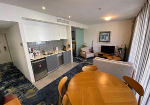 a kitchen and dining room with a wooden table in a room at Lovely One Bedroom Apartment "Cairns Harbour Lights" in Cairns