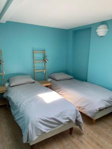 two beds in a room with blue walls at Aux Bains des Mots in Saint-Aubin-sur-Mer