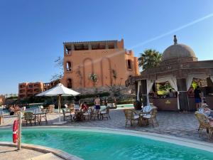 a swimming pool with tables and chairs next to a building at Dream Lagoon Resort & Aqua Park in Marsa Alam City