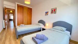 a bedroom with two beds and a table with a lamp at Apartamento Sol do Amanhã in Santa Cruz
