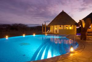 - une grande piscine en face d'une maison la nuit dans l'établissement Severin Safari Camp, à Tsavo West National Park