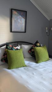 a white bed with two green pillows on it at Wayside Inn Knysna in Knysna