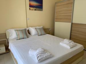 a bedroom with a large white bed with towels on it at Luxury Apartment Keramoti in Keramotí