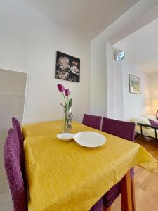 un tavolo con una tovaglia gialla e un vaso con dei fiori di Apartmani Katić a Makarska