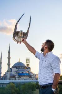 un hombre sosteniendo un pájaro frente a una mezquita en Sarnic Premier Hotel, en Estambul