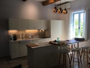 a kitchen with white cabinets and a island with bar stools at Gites Còr Causy MIMOSA in Causses-et-Veyran