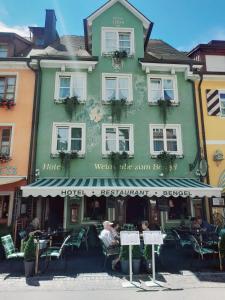 a green building with people sitting outside of it at Hotel Zum Bengel in Meersburg