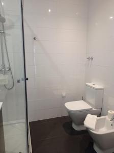 a white bathroom with a toilet and a shower at Eira da Mila in Coimbra