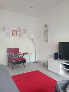 sala de estar con silla roja y TV en Eira da Mila en Coimbra