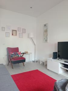 a living room with a red chair and a television at Eira da Mila in Coimbra