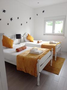 2 camas en una habitación blanca con sofá en Eira da Mila en Coímbra
