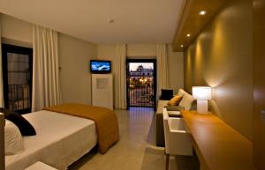 a hotel room with a bed and a couch and a television at Hotel Barrameda in Sanlúcar de Barrameda