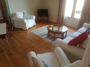 Una sala de estar con un sofá blanco y una mesa. en La Petite Cerise, en Eymoutiers
