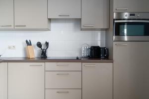 uma cozinha com armários brancos e electrodomésticos de prata em SHS HOMES-LUXE HIGHRISE, 2 BEDROOMS, KITCHEN, FREE PARKING, STUNNING VIEW, LARGE TARRASSE, Workspace em Hasselt