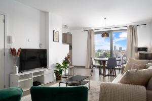 uma sala de estar com um sofá e uma televisão em SHS HOMES-LUXE HIGHRISE, 2 BEDROOMS, KITCHEN, FREE PARKING, STUNNING VIEW, LARGE TARRASSE, Workspace em Hasselt