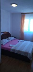 a bedroom with a bed with pink sheets and a window at Apartments Mara Seget Vranjica in Seget Vranjica