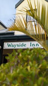 a sign that says waveride inn next to a house at Wayside Inn Knysna in Knysna
