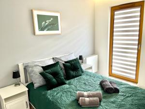 sypialnia z łóżkiem z zieloną pościelą i poduszkami w obiekcie Modern Green Apartment w Krakowie