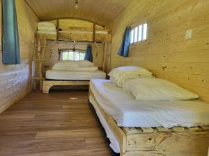 two beds in a room with wooden walls at L'alternatif in Huriel