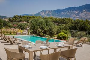 a patio with a table and chairs next to a pool at Montagna & Mare villa in Kefallonia