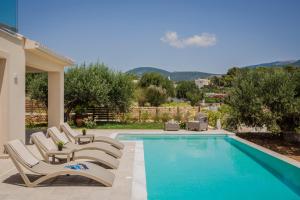 a swimming pool with lounge chairs next to a house at Montagna & Mare villa in Kefallonia