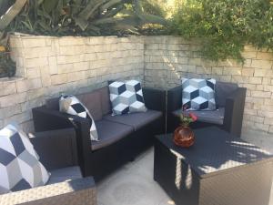 a patio with a couch and two chairs with pillows at Gites Còr Causy MIMOSA in Causses-et-Veyran