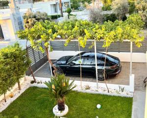 um carro preto estacionado num parque de estacionamento com árvores em White House Kokas Luxury Apartments em Kremasti