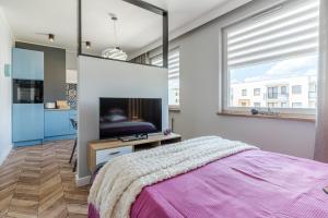 a bedroom with a bed and a flat screen tv at Lead Apartment in Grudziądz