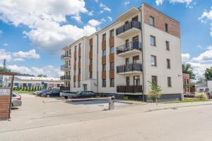 un edificio de apartamentos con coches aparcados en un aparcamiento en Lead Apartment, en Grudziądz