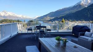 a balcony with a table and chairs and mountains at Central Lakeview Apartment with amazing rooftop 镇上湖景三室套房 in Queenstown