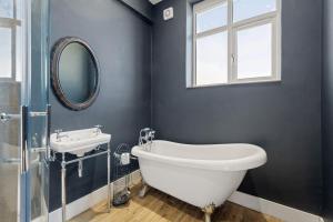 a bathroom with a tub and a sink and a mirror at The Chapel in Humby +33 photos