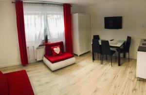 a living room with a red chair and a table at Apartament Jarzębinka in Międzyzdroje