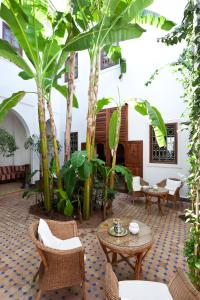 einen Innenhof mit Tischen, Stühlen und Bäumen in der Unterkunft Riad Les Bougainvilliers in Marrakesch