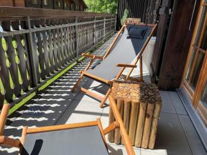 una fila de sillas de madera sentadas en un porche en Appartement 53m2 rénové dans un chalet au coeur de Charmey avec vue sur les montagnes en Charmey