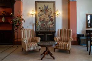 two chairs and a table and a painting on the wall at Hospedarte Palacete Real in El Rocío