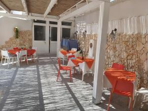 a restaurant with red tables and chairs and a stone wall at Lido Di Procida Guest House in Procida