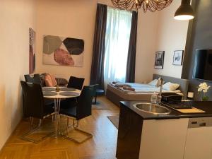 ein Zimmer mit einer Küche und einem Wohnzimmer mit einem Tisch in der Unterkunft Stylish Apartment by the Vígszínház Theater in Budapest