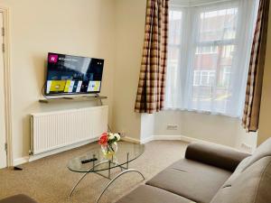 ein Wohnzimmer mit einem Sofa und einem TV in der Unterkunft Clive Crest house in Portsmouth