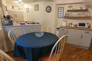 eine Küche mit einem Tisch und einem blauen Tischtuch darauf in der Unterkunft Anne Cottage, Bakewell, in the Peak District in Bakewell