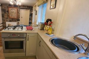 une cuisine avec un évier et une cuisinière dans l'établissement Anne Cottage, Bakewell, in the Peak District, à Bakewell