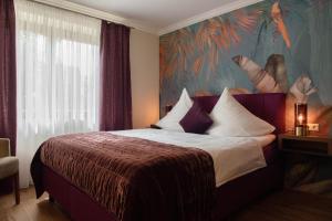 a hotel room with a bed with a painting on the wall at Boutique - Hotel Zum Schloss in Amtzell