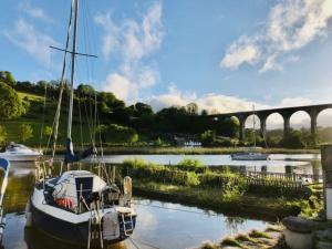 un barco está atracado en el agua cerca de un puente en Cornish family holiday lodge, Private Hot Tub & Shared Pools, en Callington