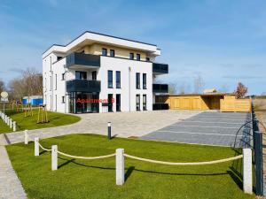 um grande edifício branco com um parque infantil em frente em Haus Meerruhe Karlshagen Apartment 1-6 em Ostseebad Karlshagen