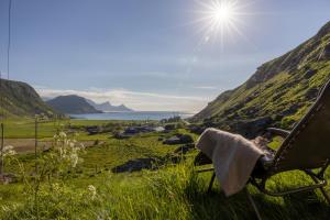 a chair sitting on a hill with a view of the ocean at Feriehus med flott havutsikt ved Hauklandstranden in Leknes