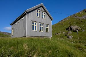 a gray house on a hill with grass at Feriehus med flott havutsikt ved Hauklandstranden in Leknes
