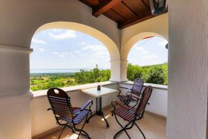 a balcony with chairs and a table and two windows at Fishing & Golf Kisleshegy Balatonudvari Vendégház in Balatonudvari