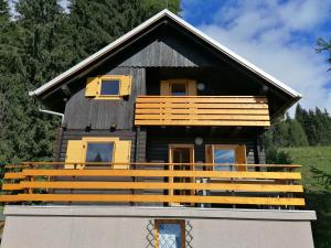 Cabaña de madera con puertas amarillas y balcón en Karavanke mountain hut, en Jesenice