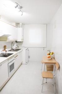 una cucina bianca con elettrodomestici bianchi e tavolo in legno di Apartamento Dos Valles ad Aínsa